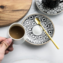 Lade das Bild in den Galerie-Viewer, Kaffeetasse mit Unterteller in schwarz-weißen Muster und goldenen Akzenten inkl. goldenem Löffel
